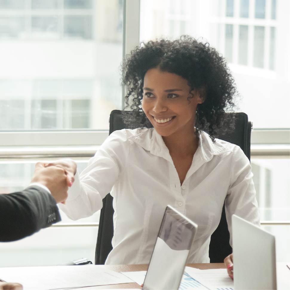 woman in an office shaking hands in agreement and smiling